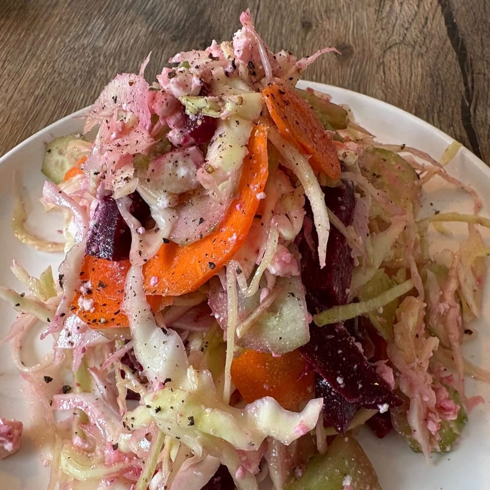 Close-up of a vibrant Italian salad with shredded cabbage, carrots, beets, and a creamy dressing.