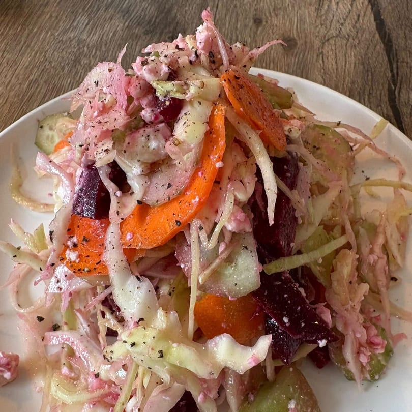 Close-up of a vibrant Italian salad with shredded cabbage, carrots, beets, and a creamy dressing.
