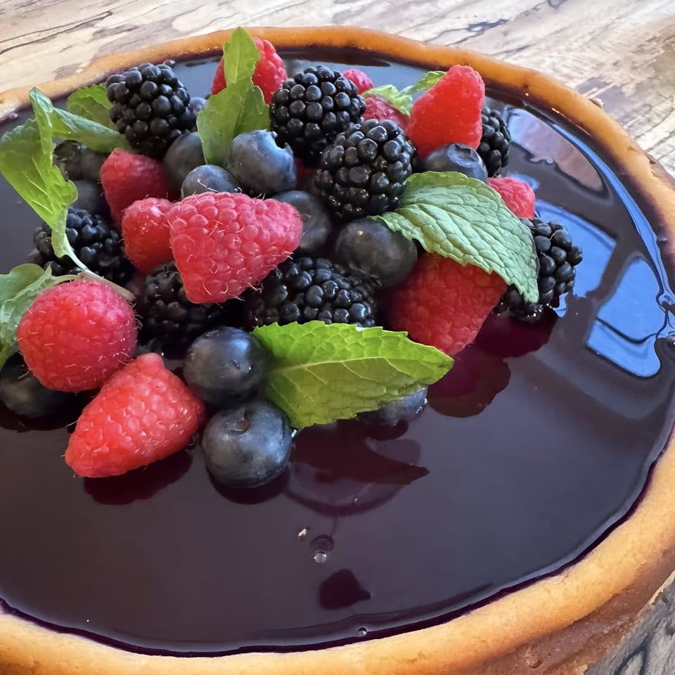 A Mambo Italiano berry tart with a dark glaze, topped with fresh raspberries, blueberries, blackberries, and mint.