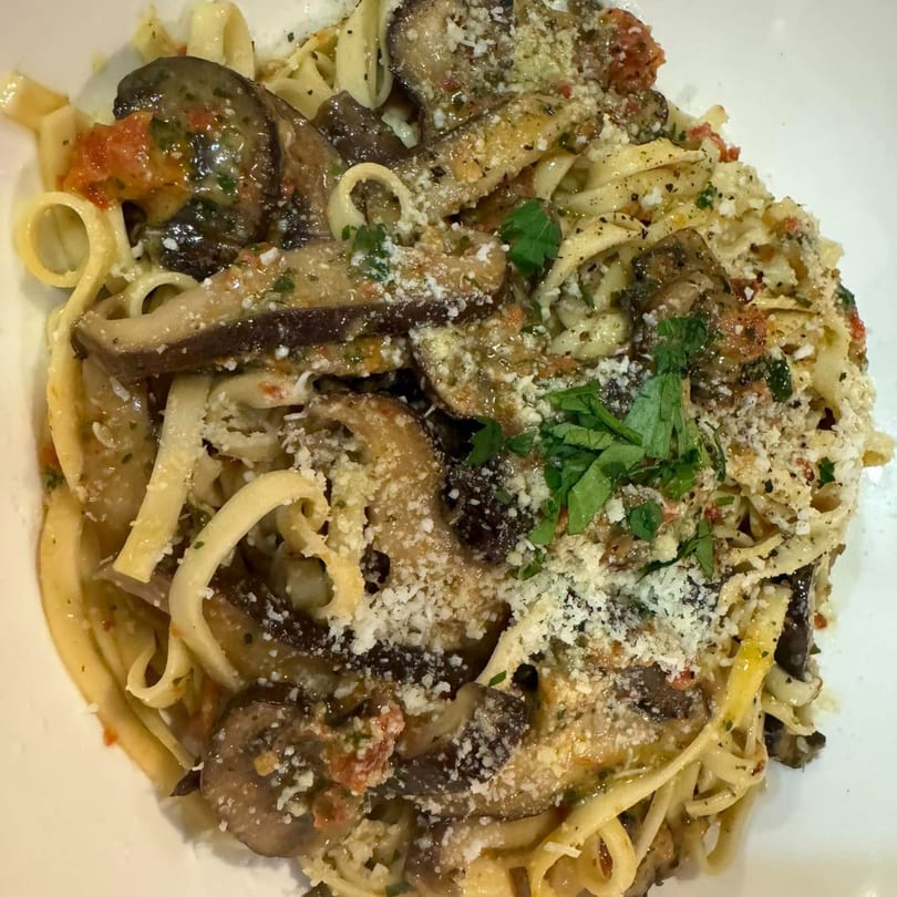 Mambo Italiano's fettuccine pasta with mushrooms, tomatoes, and parmesan cheese, garnished with parsley.